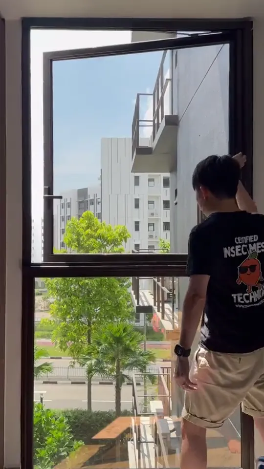 Installer checking insect mesh fitted across a full-height apartment window